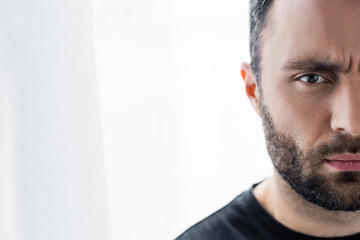 Fototapeta premium partial view of thoughtful, handsome bearded man looking at camera