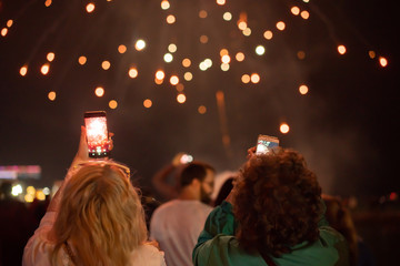 View from the back at people shooting fireworks on the phone defocused image, festive concept.