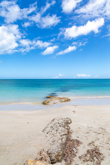 Rocks on an Antiguan beach, with a turquoise sea behind and blue sky overhead