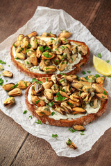 Homemade Mussels on grilled bruschetta, toast with soft cheese and herbs