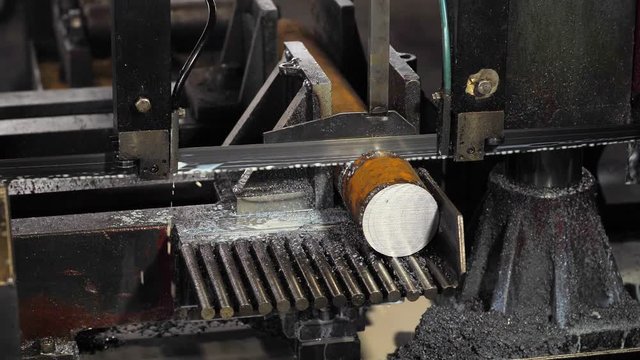 Contour bandsaw in the workshop.Band saw cutting metal, cooling emulsion is poured on the saw.The work contour band saw close-up.Band contour Saw cuts metal contour disc.