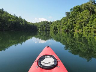 Red kayak on a beautiful summer morning in Lake Santeetlah, North Carolina, with forested hills...