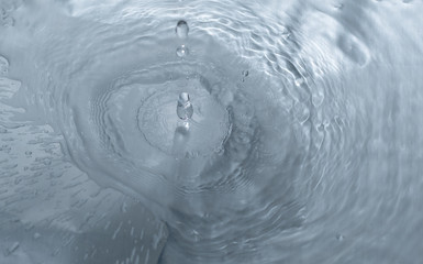Wassertropfen fallien in das blaue wasser mit wellen