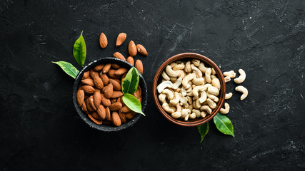 Nuts Cashew and Almond in a bowl on a black background. Top view. Free space for your text.
