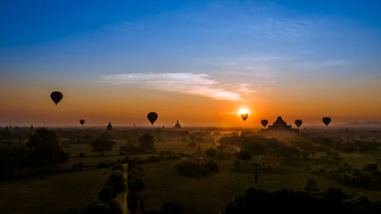 Sunrise in Bagan, Myanmar Burma with hot air balloon in front of sun and pagodas