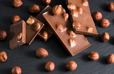 Milk or dark chocolate with nuts on black background.