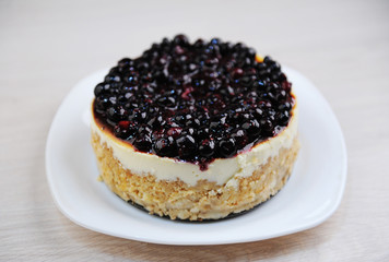 Whole blueberry cheesecake on a white plate