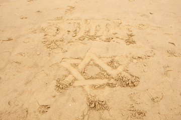 Star of David drawn on the sand beach in Tel Aviv, Israel and over it the name of God in Hebrew...