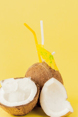 Fresh Coconut cocktail with a straws on yellow background, copy space
