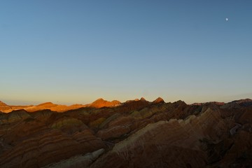 Small moon and colorful hills known as Rainbow mountains of China during sunset in Zhangye Danxia Landform Geological Park, Gansu province, China