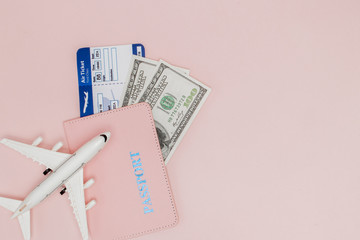 Passport, dollars, plane and air ticket on a pink background. Travel concept, copy space