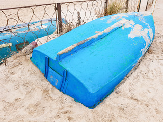 Fototapeta na wymiar Blue fishing boats lie on the sandy beach