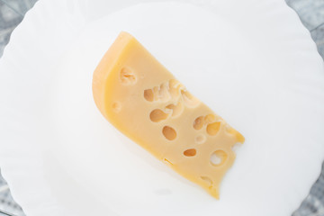 a piece of cheese with holes is on a white plate