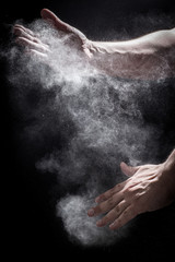 Moody, Shadowy High-Speed Photo of a Caucasian Man's Hands Clapping Together in an Explosion of Dust and Powder - with a Black Background