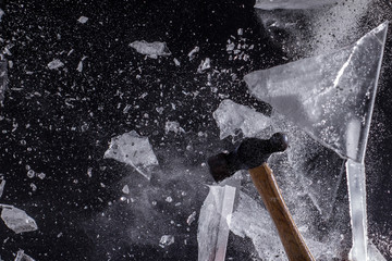 Moody, Shadowy High-Speed Photo of a Ball-Peen Hammer Smashing through a Sheet of Ice - Exploding in a Cloud of Dust and Shards with a Black Background