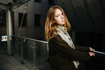 beautiful girl in coat with scarf walks on city street, portrait of woman resting outdoors