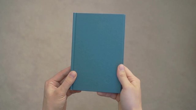 Two hands opening a book with blank pagesTwo hands opening a blank book. Can be used as a blank template. Holding the book with two hands, it is opened and then closed.