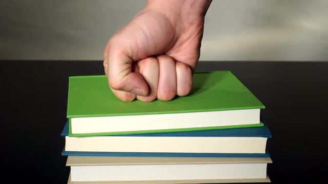 Hitting the books literal idiomHit the books, literally. A fist pounding a stack of books piled up. Hitting the books.