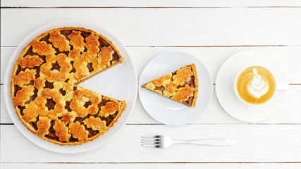 Homemade pie with cottage cheese and prunes and cup of coffee.