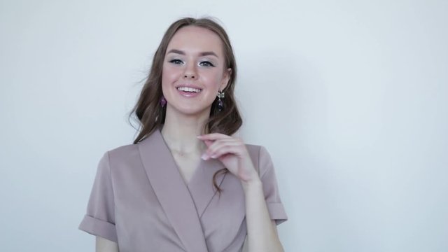 Cute girl smiling model posing in a gray dress on a gray background .Slow motion