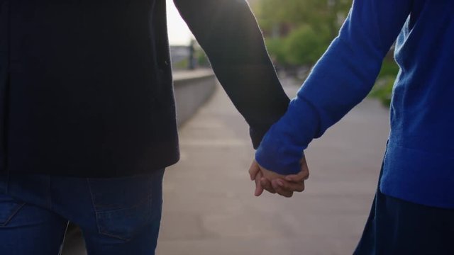 Young diverse couple holding hands as the camera follows behind, in slow motion
