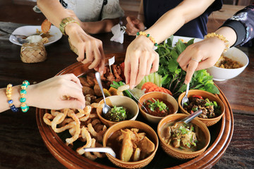 Many hands are picking up food.