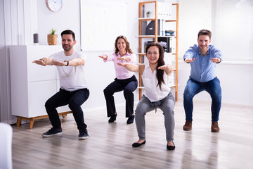 Businesspeople Doing Sit-ups In Office