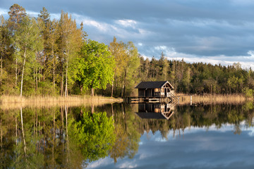 Obraz premium Small fishing hut on calm lake in late afternoon