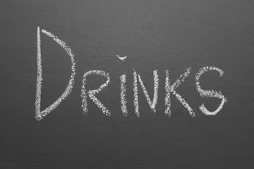 Hand-written lettering with chalk "drinks" on a gray board