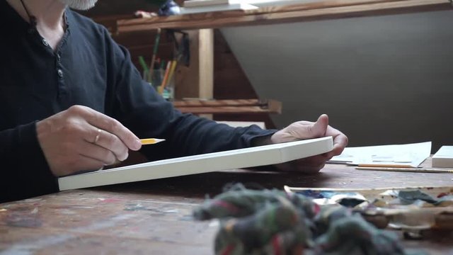 Side shot of the hands of male artist, drawing sketch at paper in his studio.