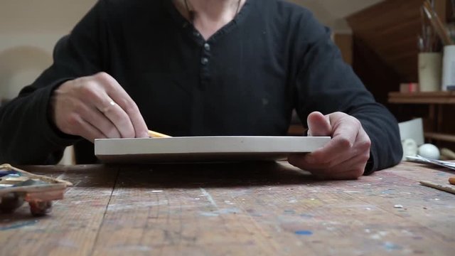 hands of male artist, drawing sketch at paper in his studio.