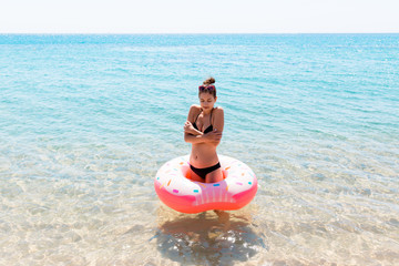 Woman swimming with inflatable donut in cold shivering sad crossed arms black bikini swimsuit...