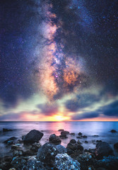 Abstract Milky way galaxy with sunset at the sea and rocks