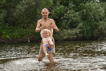 Fototapeta premium father teaching his little son to swim, they are happy. hot summer day. happy family on the beach.