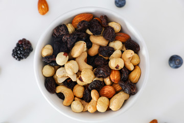 Nuts and berries are scattered on the table. nuts are in the plate.