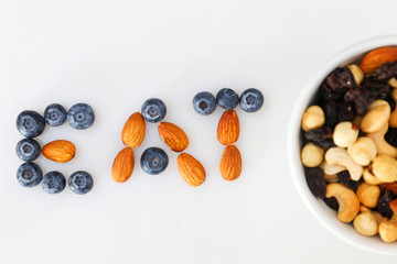 The word eat is laid out of nuts and blueberries. Assorted nuts and berries.