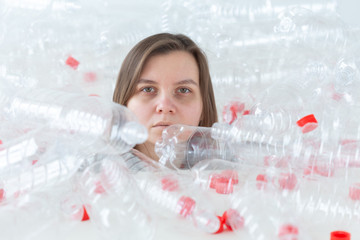 Plastic pollution problem and environment protection. Weak tired woman in a pile of plastic bottles. Save Earth concept. Clean our nature.