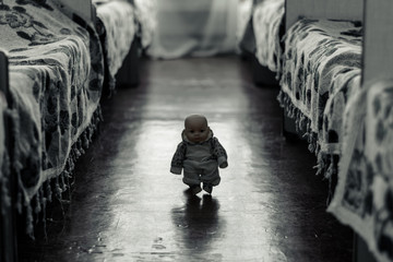 Little scary doll walks between the beds - obrazy, fototapety, plakaty