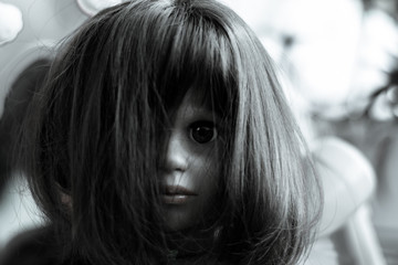 The face of a creepy girl doll with long hair. Doll face closed by hairs