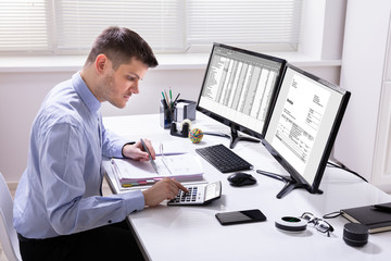 Obraz na płótnie Canvas Side View Of Businessman Checking Invoice On Computer