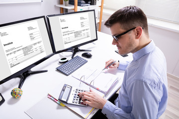 Fototapeta na wymiar Businessman Calculating Invoice In Office