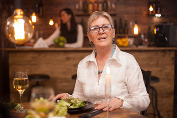Portrait of nice old lady looking at the camera while enjoying her meal in a restaurant.