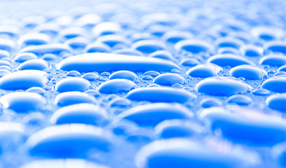 Obraz premium Transparent still water drops on light blue background. Blue water drops. Drops of rain on glass. Blue abstract water drop background. Water surface