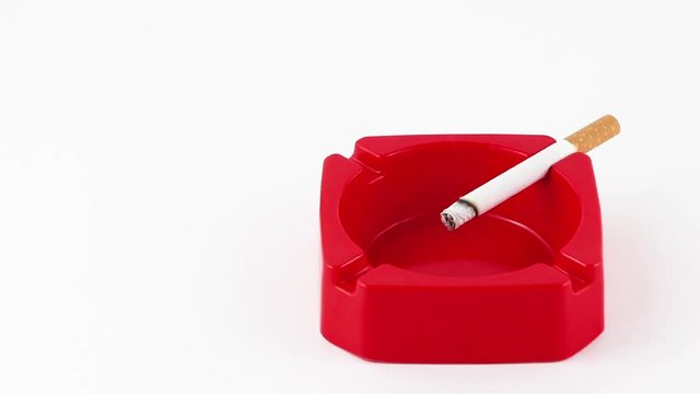 Una sigaretta si consuma in un posacenere di colore rosso