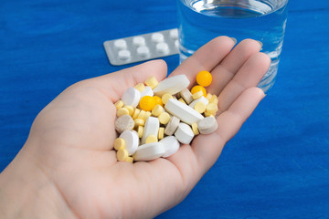  many pills in hand on blue background