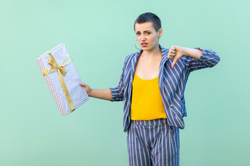 Portrait of unsatisfied with short hair young woman in striped suit standing, showing dislike...