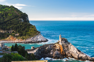 Naklejka premium Stunning Church of Saint Peter (Chiesa di San Pietro) built on rugged sheer cliffs surrounded by the turquoise water of the Gulf of Poets in Porto Venere, La Spezia, Italy, as seen from above.