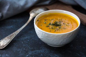 Pumpkin cream soup. Fresh soup with herbs on a background, Autumn concept. Tasty healthy food.