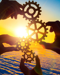 Four hands collect the gears of the puzzles. against the background of sunlight. Concept business idea. Teamwork, partnership, strategy, cooperation