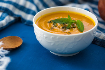 Pumpkin cream soup. Fresh soup with herbs on a background, Autumn concept. Tasty healthy food.